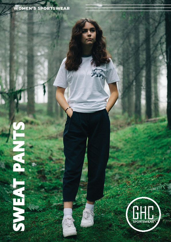 Woman wearing custom women's sweat pants and a graphic t-shirt, standing in a forest, showcasing comfortable and stylish sportswear designed for outdoor adventures.