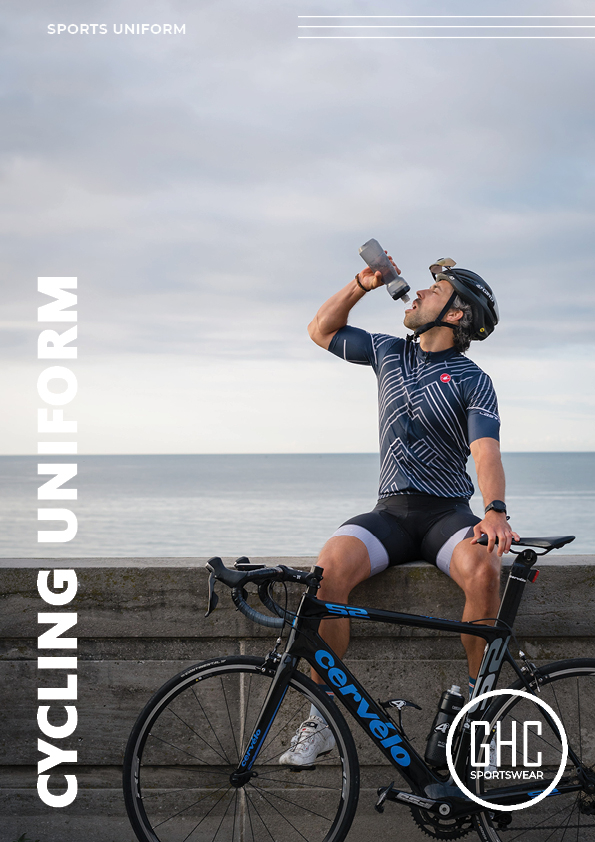 A cyclist wearing a custom cycling uniform, sitting on a stone wall with a bicycle, drinking water, and enjoying the view by the sea. Available at ghcsportswear.com.