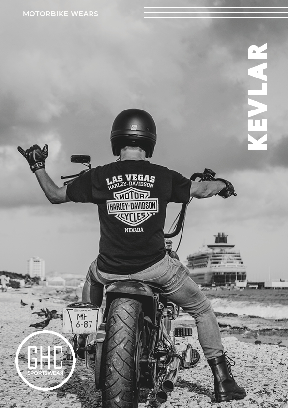 A motorbike rider wearing Kevlar jeans and a Harley-Davidson t-shirt, seated on a Harley-Davidson motorcycle at a beachside location. The rider, facing away from the camera, has both arms raised in a triumphant gesture, showcasing the sturdy and stylish Kevlar gear by GHC Sportswear.