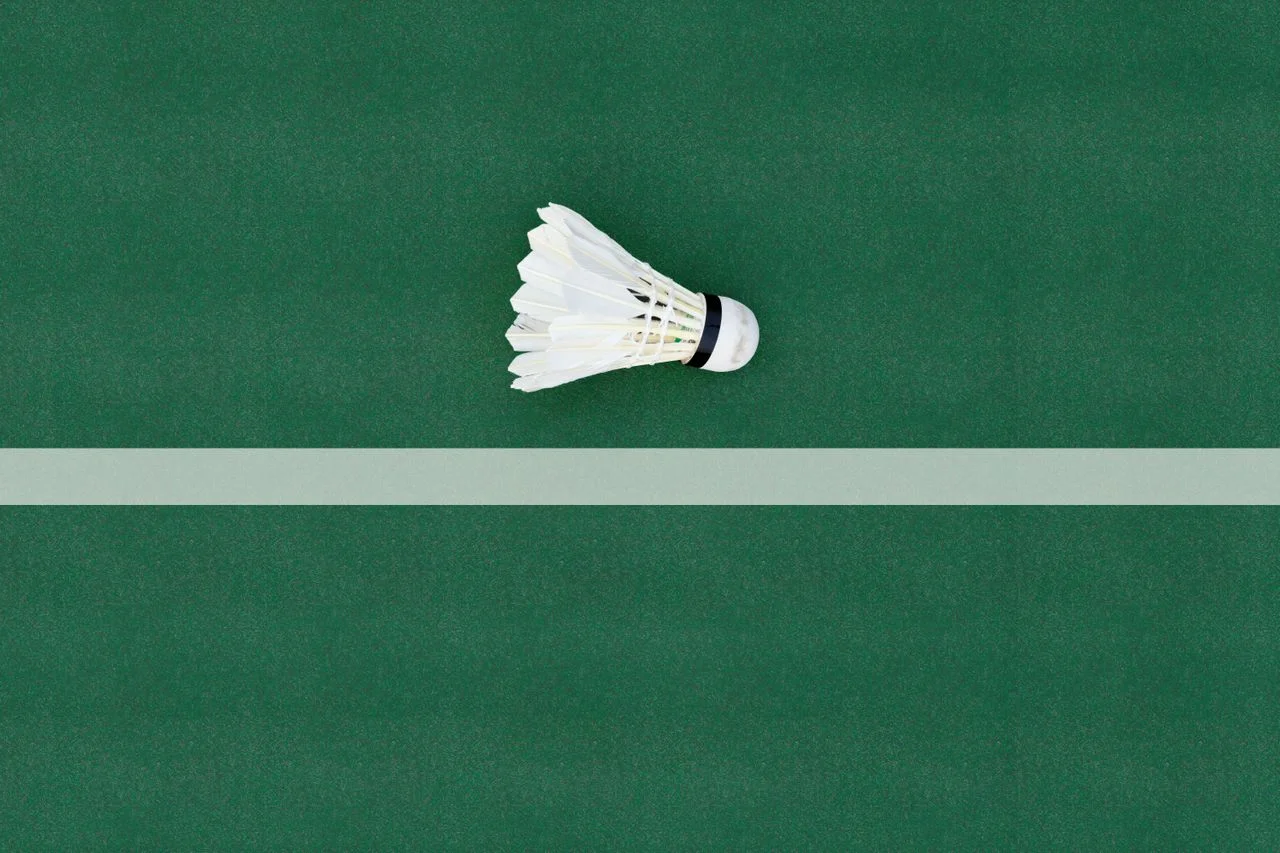 Life of a badminton shuttlecock shown on an indoor court with a ruffled feather shuttle, custom badminton apparel, and a player lunging during a rally.