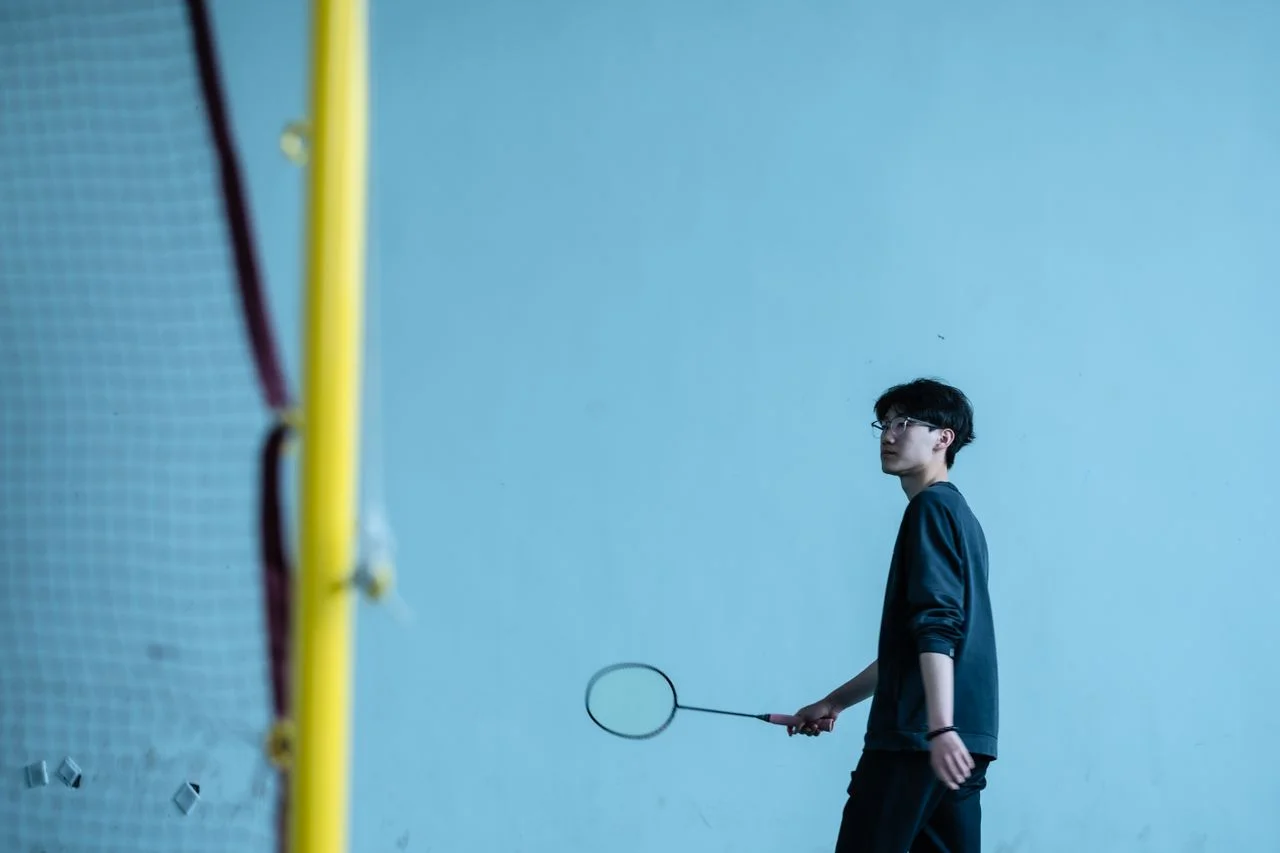 Virtual reality in badminton training with a player using VR headset, racket, digital footwork markers, and custom badminton apparel on an indoor court.