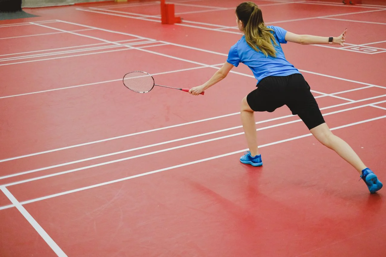 Badminton drills on an indoor court with players practicing footwork, multi-shuttle training, net kills, serve accuracy, and custom badminton apparel.