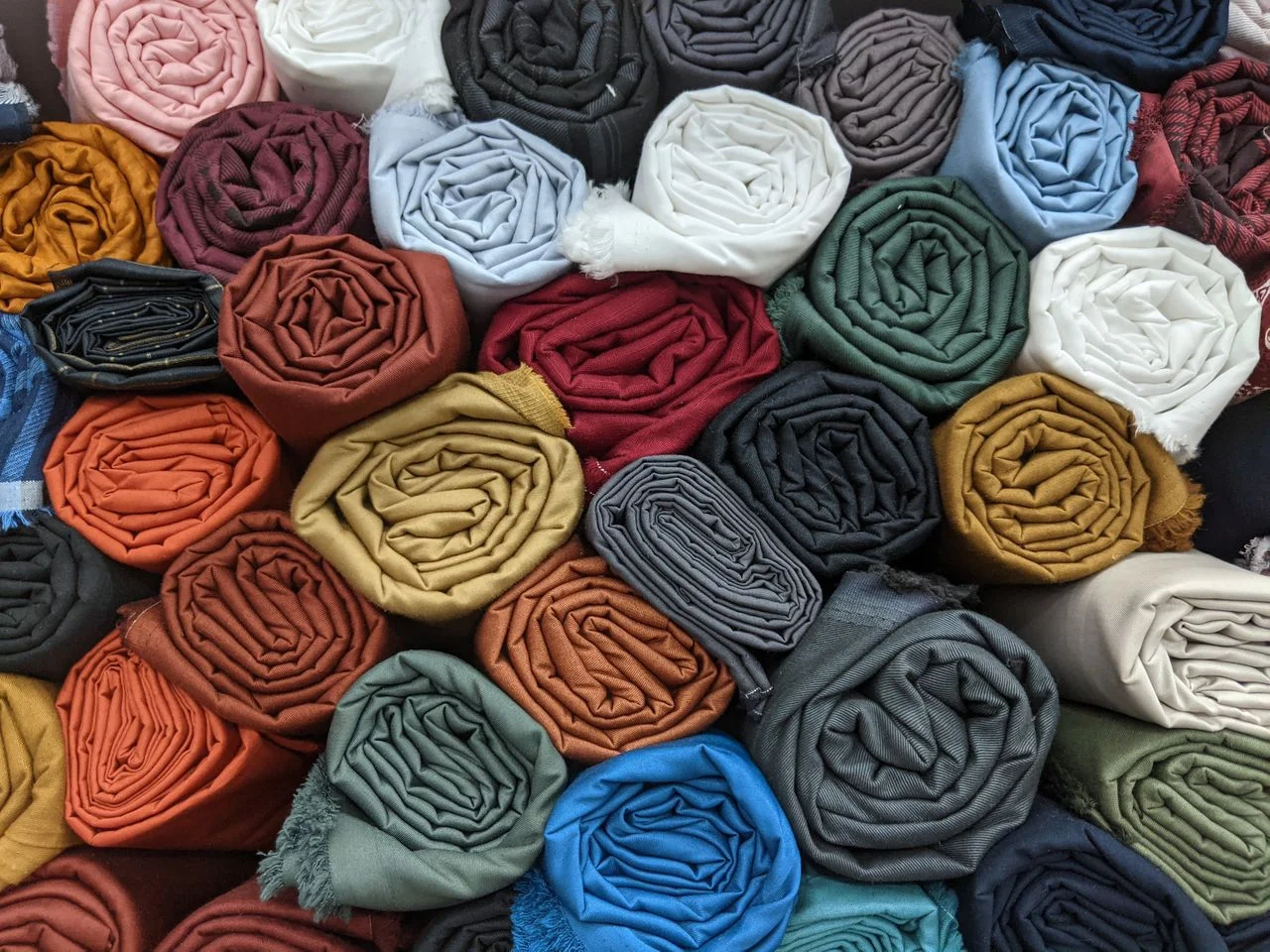 Fabric and trim sourcing table with fabric swatches, lab dips, zippers, thread, elastic, labels, quality tests, BOM, and bulk apparel planning.