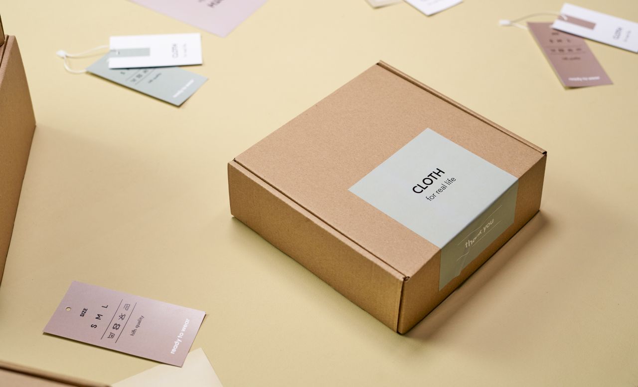 Private label packaging samples with folded clothing, garment bags, hangtags and a paper retail box.